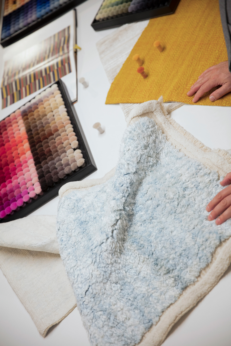 Designer sketching a custom rug concept with samples and digital tools